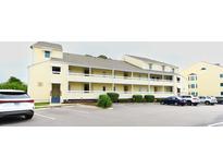 Charming condominium exterior with yellow siding, multiple balconies, and ample parking at 1100 Possum Trot Dr. # D106, North Myrtle Beach, SC 29582