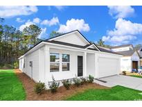 Charming one-story home featuring white siding, black door, attached garage, and a neatly landscaped front yard at 1217 Willow Oaks Way, Conway, SC 29526
