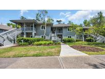 Two-story condo building with gray siding and well-maintained landscaping under a partially cloudy sky at 1221 Tidewater Dr. # 122, North Myrtle Beach, SC 29582