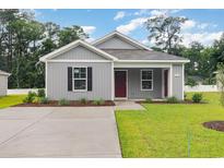 Charming gray one-story home with a well-manicured lawn and a welcoming red front door at 1710 Whispering Pine St., Ocean Isle Beach, NC 28469