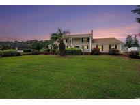 Stately brick home with a sprawling lawn, mature landscaping, and a columned front porch evoking Southern charm at 328 Waterside Dr., Myrtle Beach, SC 29577