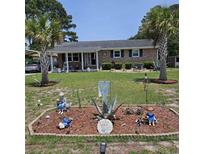 Charming brick home with well-maintained lawn, mature palm trees, and unique garden decor at 4083 Sand Trap Ave., Little River, SC 29566