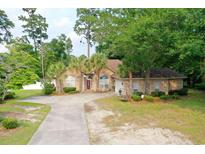 Charming brick home with mature landscaping, long driveway, and a well-manicured front yard at 4447 River Rd., Little River, SC 29566