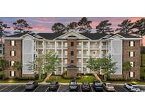 Inviting three-story condo building with white balconies and well-manicured landscaping and parking at 4878 Luster Leaf Circle # 102, Myrtle Beach, SC 29577