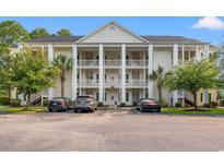 Three-story condo building with white columns and balconies, surrounded by trees and a parking lot at 6000 Windsor Green Way # 104, Myrtle Beach, SC 29579