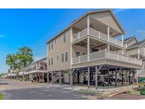 Coastal home on stilts, boasting multiple balconies, covered parking, and beachy charm against a clear blue sky at 6001- 8005 S Kings Hwy., Myrtle Beach, SC 29575