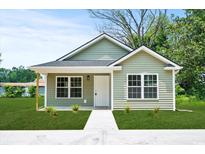 Charming single-story home with light green siding, a well-manicured lawn, and a concrete walkway to the front door at 608 Miles Ct, Marion, SC 29571
