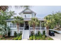 Charming two-story coastal home featuring a welcoming front porch, lush landscaping, and a convenient golf cart at 70 Beachwalker Ct., Georgetown, SC 29440