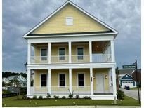 Charming two-story yellow home featuring double porches with white railing and columns at 8163 Wood Pass Lane, Myrtle Beach, SC 29572