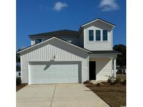 Two-story home featuring a two-car garage, bright white siding, black roof, and manicured landscaping at 859 Long Beach Dr, Longs, SC 29568
