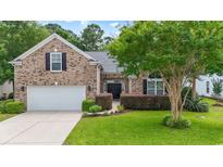 Charming brick home featuring a well-manicured lawn, double-door entrance, and attached two-car garage at 106 Cypress Creek Dr., Murrells Inlet, SC 29576