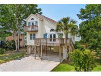 Charming beach home featuring a spacious deck, complemented by a well-maintained yard and a convenient ground-level carport at 154 Cedar Point Ave., Murrells Inlet, SC 29576