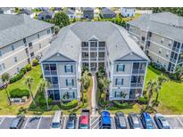 Aerial view of condominiums with multiple stories, balconies, convenient parking, and lush landscaping at 2020 Cross Gate Blvd. # 203, Surfside Beach, SC 29575