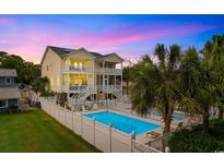 Inviting coastal home boasts a private pool, white picket fence, and multiple balconies perfect for outdoor relaxation at 213 South Myrtle Dr., Surfside Beach, SC 29575