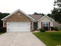 Charming single-story home with brick accents, attached garage, and well-maintained lawn at 266 Tall Palms Way, Little River, SC 29566