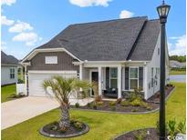 Charming home featuring a well-manicured lawn, stone accents, and a welcoming covered front porch at 305 Portofino Dr., Myrtle Beach, SC 29579