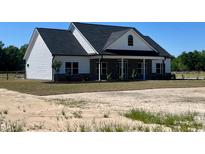 Inviting two-story home with white siding, a black roof, and a charming front porch perfect for relaxing at 3200 Fowler School Rd., Loris, SC 29569