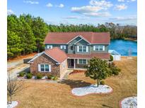 Beautiful two-story home featuring a brick and siding exterior, well-manicured lawn, and a serene lake view at 400 Dog Pen Ct., Myrtle Beach, SC 29588