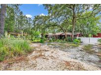Ranch-style home featuring a cozy yard and a large, gravel driveway surrounded by mature trees and natural foliage at 5114 Cowart Ct., Murrells Inlet, SC 29576