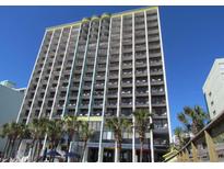 Brightly painted condominium exterior with large balconies and palm trees against a clear blue sky at 6804 N Ocean Blvd. # 1023, Myrtle Beach, SC 29572
