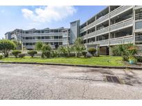 This building has multi-level balconies, a grassy area with shrubs, and plenty of parking for all its tenants at 1101 Possum Trot Rd. # D201, North Myrtle Beach, SC 29582