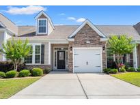 Charming home featuring a stone-accented facade, attached garage, and well-maintained landscaping with green lawn at 121 Parmelee Dr. # D, Murrells Inlet, SC 29576