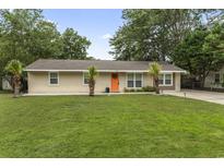 Charming brick home featuring a manicured lawn and an eye-catching orange front door at 1223 Naylor Ave., Myrtle Beach, SC 29577