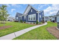 Charming blue two-story home with white trim, manicured lawn, and paved walkway on a sunny day at 2080 Silver Island Way, Murrells Inlet, SC 29576
