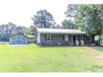 Charming single-story home featuring a metal roof, welcoming front porch, and spacious yard with an outbuilding at 3150 Dusty Rd., Loris, SC 29569