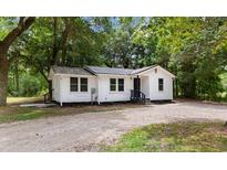 Charming white cottage-style home with a metal roof, gravel driveway, and mature trees at 3519 Cates Bay Hwy., Conway, SC 29527