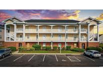 A beautiful three-story condo building with brick base, charming balconies, and accessible parking, set against a colorful sunset at 3983 Forsythia Ct. # 301, Myrtle Beach, SC 29588