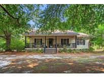 Charming home with a covered front porch and rocking chairs, set amidst mature trees at 8506 Old Nichols Hwy., Nichols, SC 29581
