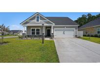 Charming single-Gathering home featuring a gray exterior, well-maintained lawn, and an attached garage with a concrete driveway at 8761 Nw Nashville Dr., Calabash, NC 28467