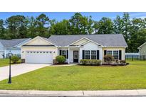 Charming single-story home with manicured lawn, an attached garage, and a beautifully landscaped front yard at 104 Browns Hollow Ct., Loris, SC 29569