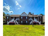 Charming townhome featuring a well-manicured lawn and appealing architectural details, including white staircases and a brown facade at 1101 Peace Pipe Pl. # 104, Myrtle Beach, SC 29579