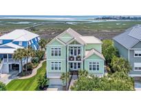 Charming two-story home with a lush green lawn and inviting front porch overlooking the serene marsh and ocean beyond at 191 Grackle Ln., Pawleys Island, SC 29585