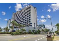 Low angle view of a modern condominium with an ocean view and a blue and white facade and palm trees at 2001 S Ocean Blvd. # 815, Myrtle Beach, SC 29577