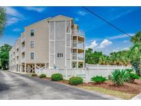 Attractive condo building with white fencing, landscaping, and exterior staircases and balconies at 211 N Hillside Dr. # 204, North Myrtle Beach, SC 29582