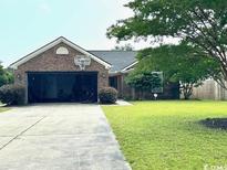 Charming brick home with a well-manicured lawn and a basketball hoop over the garage at 2707 Canvasback Trail, Myrtle Beach, SC 29588
