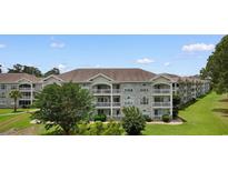 Attractive condo building with three stories and multiple balconies overlooking a lawn at 4673 Wild Iris Dr. # 21-201, Myrtle Beach, SC 29577