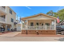 Charming home featuring a covered porch with decorative railings and a well-maintained lawn at 6001-N2 S Kings Hwy., Myrtle Beach, SC 29575