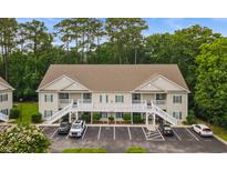 Inviting two-story condo with tan siding, green shutters, white stairs, and ample parking at 100 Lazy Willow Ln. # 103, Myrtle Beach, SC 29588
