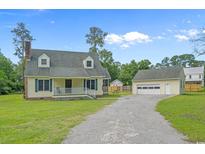 Charming two-story home with yellow siding, a white porch, and a detached garage on a large lot at 124 Wicklow Way, Pawleys Island, SC 29585