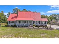 Charming home featuring a red metal roof, cozy front porch, manicured lawn, and classic curb appeal at 1700 Longleaf Dr., Myrtle Beach, SC 29575