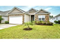 Charming single-story home featuring a stone facade, attached garage, and well-maintained front lawn with a young palm tree at 234 Rolling Woods Ct., Little River, SC 29566