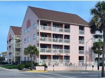 Charming three-story condo with a pink exterior, white railings, balconies, and a well-maintained landscape at 2710 S Ocean Blvd. # 402, Myrtle Beach, SC 29577
