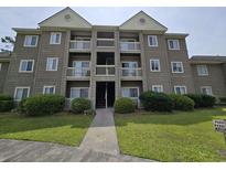Exterior shot of a multi-story condo building featuring a welcoming entrance, multiple balconies, and lush landscaping at 300-J Myrtle Greens Dr. # J, Conway, SC 29526