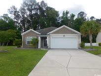Charming single-story home with a well-maintained lawn, palm trees, and a two-car garage at 401 Quinta St., Longs, SC 29568