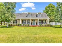Charming home featuring dormers, a cozy front porch, and a lush green lawn at 553 Fox Chase Dr., Conway, SC 29527