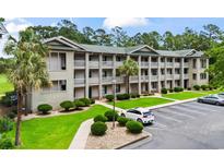 Three-story condo building with lush landscaping and well-maintained parking area at 562 Blue Stem Dr. # 54-F, Pawleys Island, SC 29585